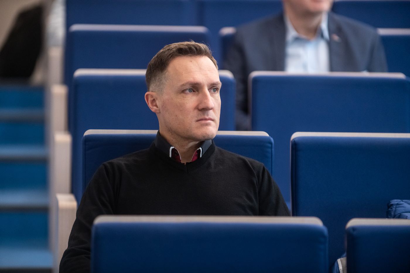 Michal Dylon seated in a lecture hall